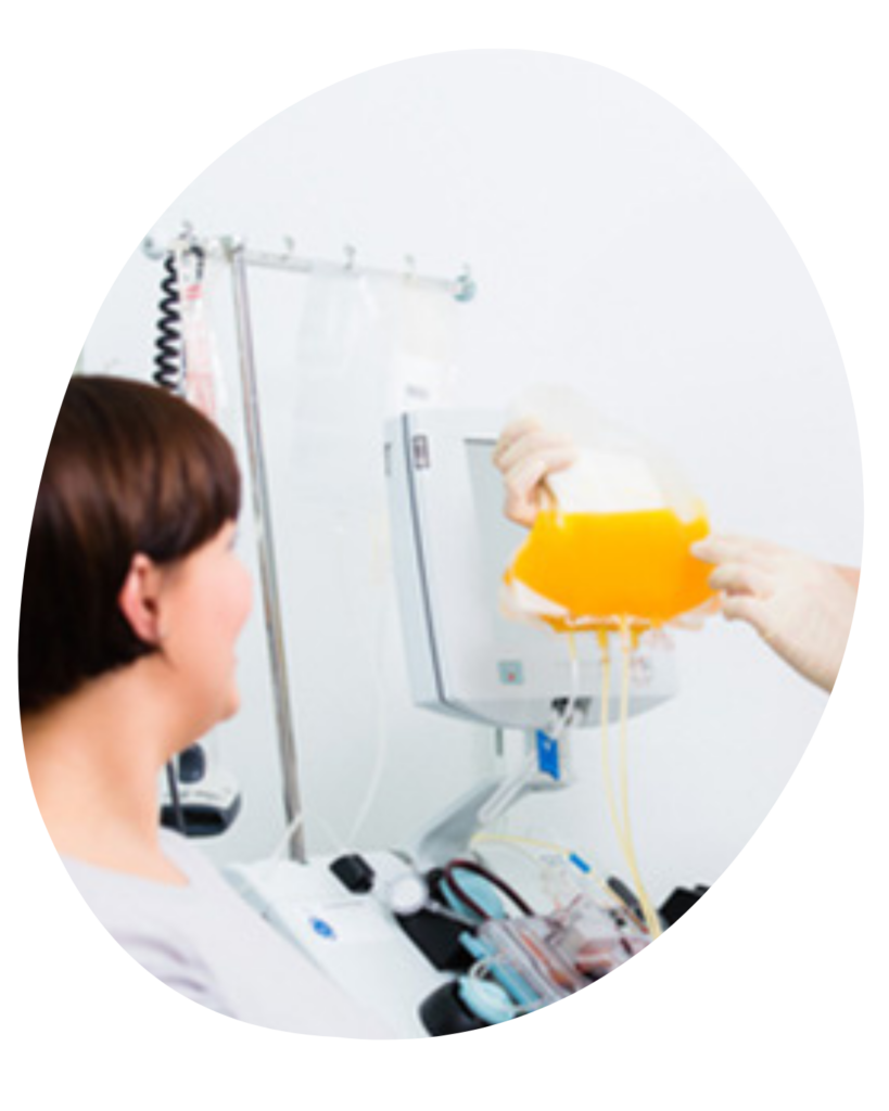 A woman donating plasma as the phlebotomist checks the plasma collection bag.