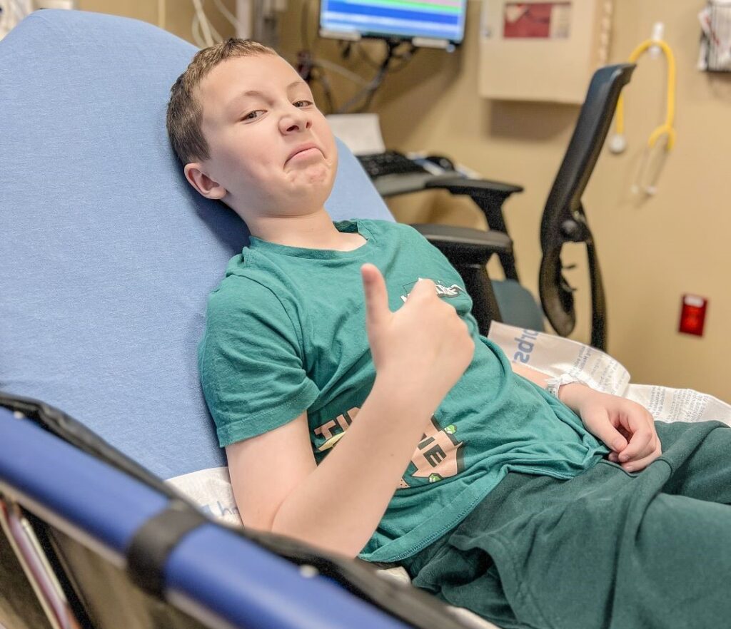 Blood donor giving the thumbs up in a donation chair.